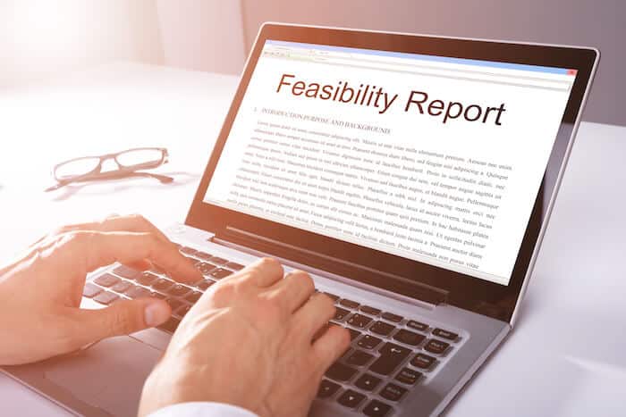 Feasibility study: person writing a feasibility report using a laptop