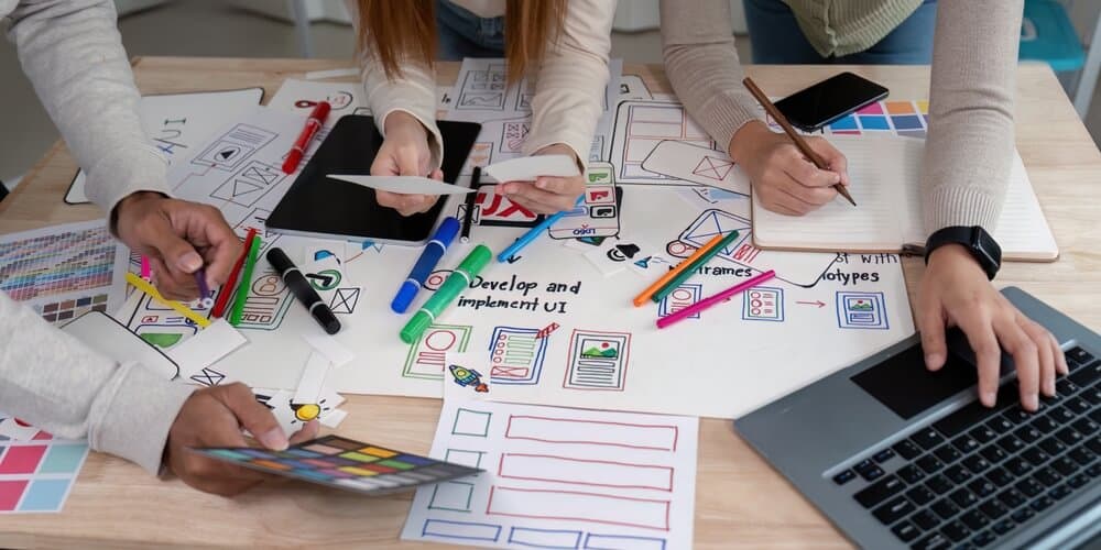 Group of people around a table coming up with designs that will be easy for product production.