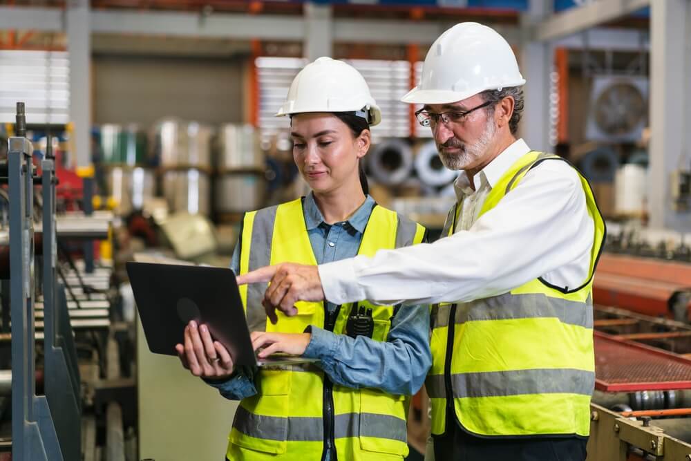 Two USA manufacturing workers talking about strategies on a device.