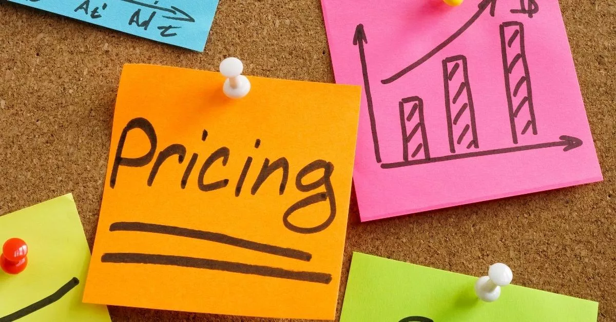A corkboard with colorful sticky notes shows the word pricing and a simple upward chart, like someone mapping out costs and growth ideas