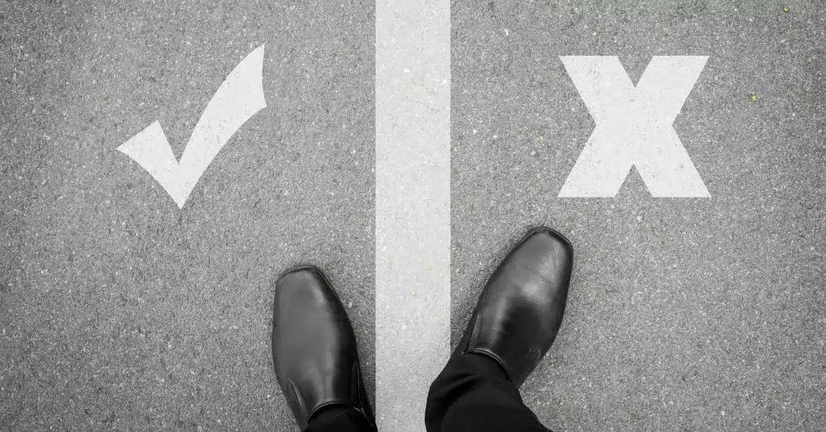 Person standing between a check mark and an X, symbolizing the decision founders face when choosing between a sourcing agent and a full-service product development company.