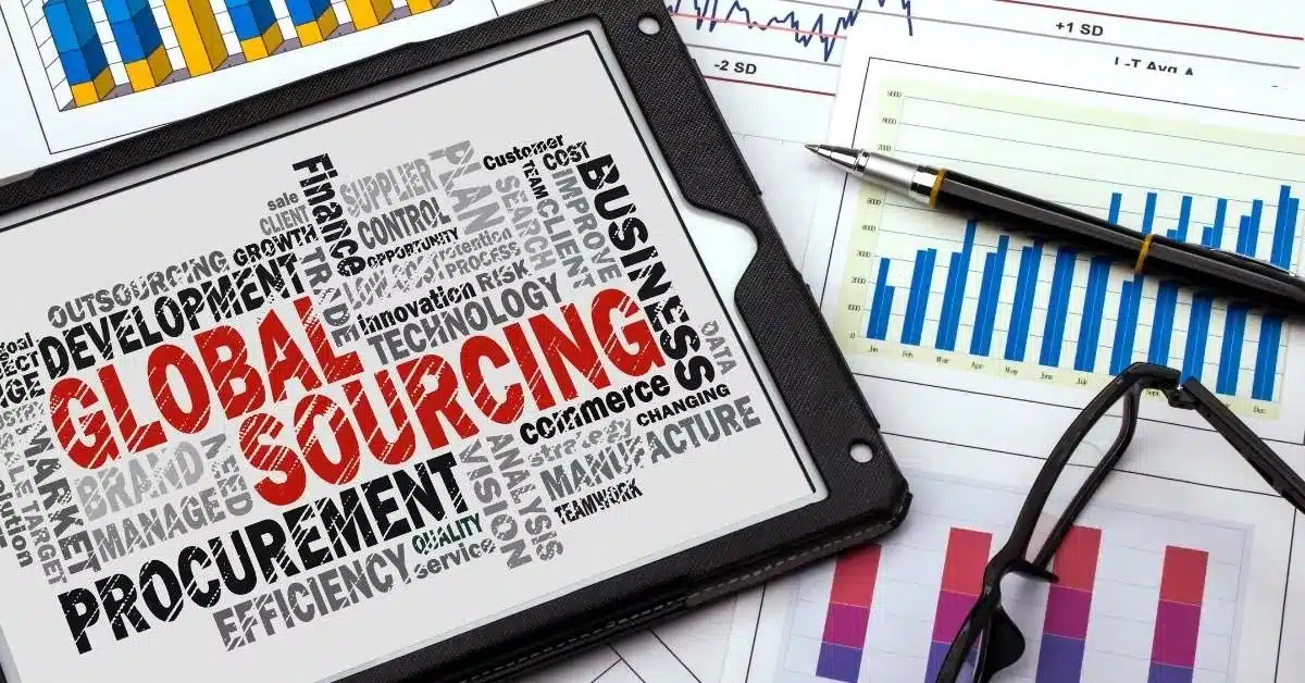 Tablet displaying “Global Sourcing” surrounded by business reports and charts, illustrating the role of sourcing agents in connecting brands with manufacturers and managing supplier relationships.