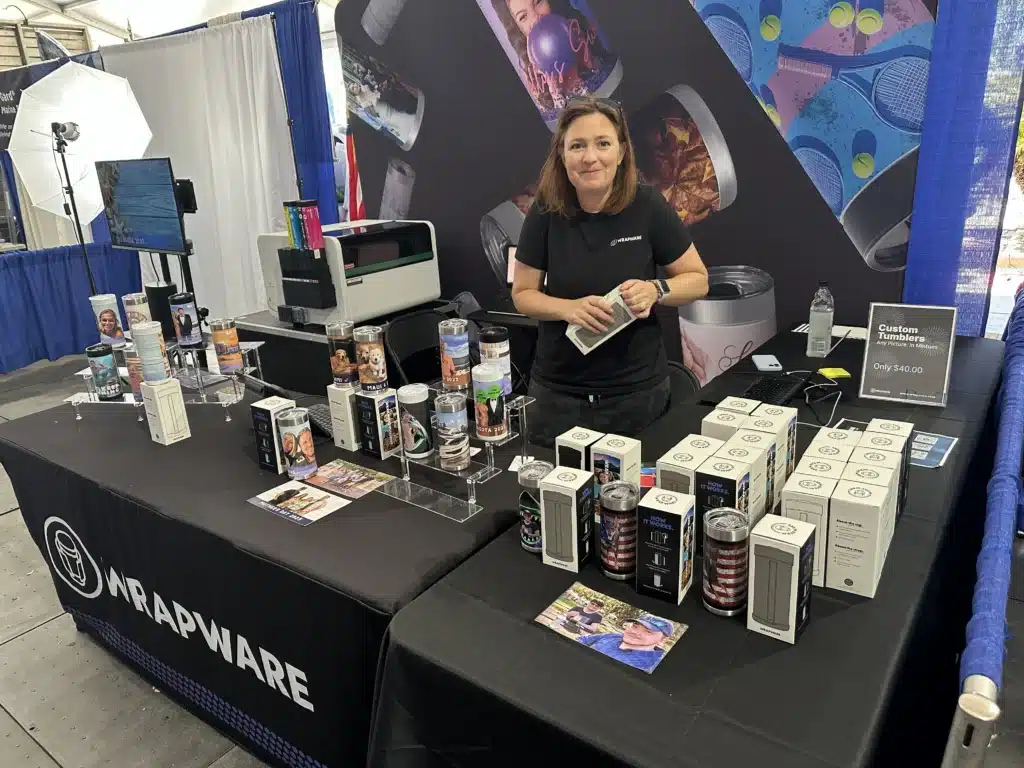 Wrapware custom printed tumblers displayed at a live event booth with Michele Davolos
