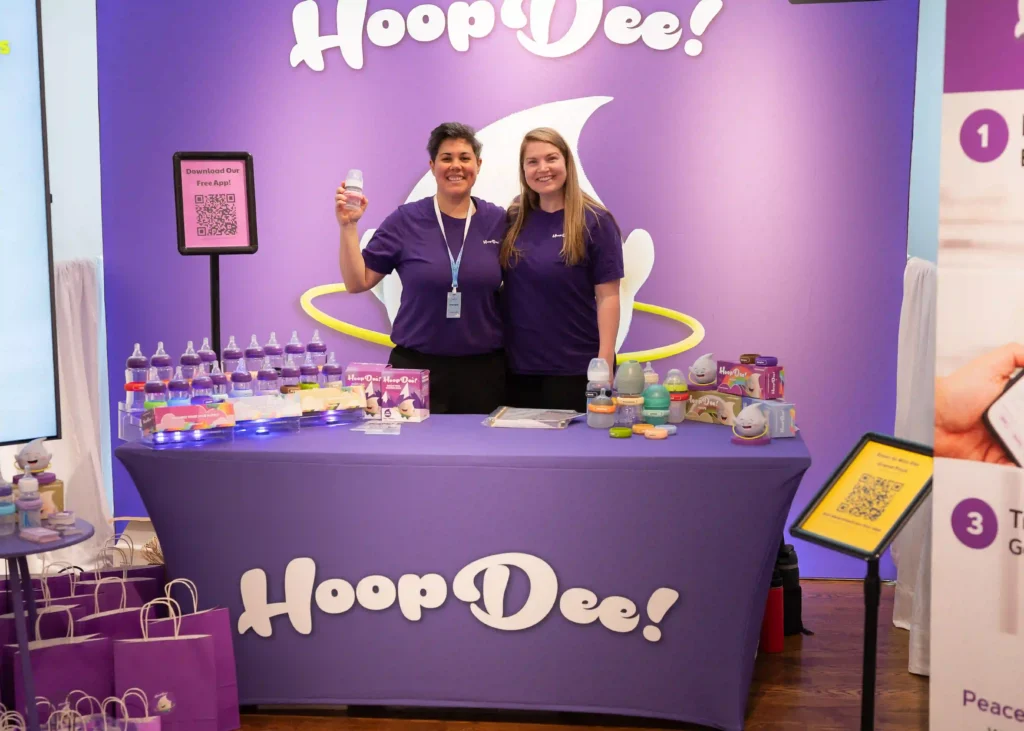 HoopDee team at their Prego Expo booth with the purple Hoop display and app download QR codes