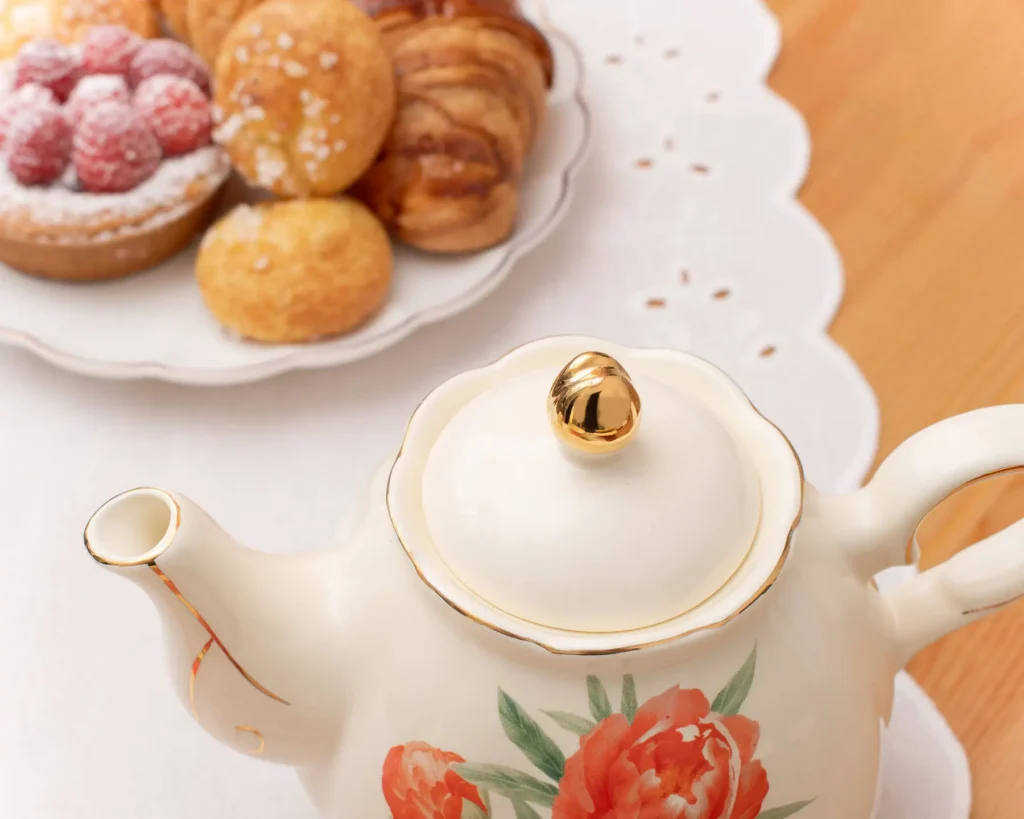 Close-up of the Peaceful Pursuits peony teacup showing the gold-trimmed scrolled handle