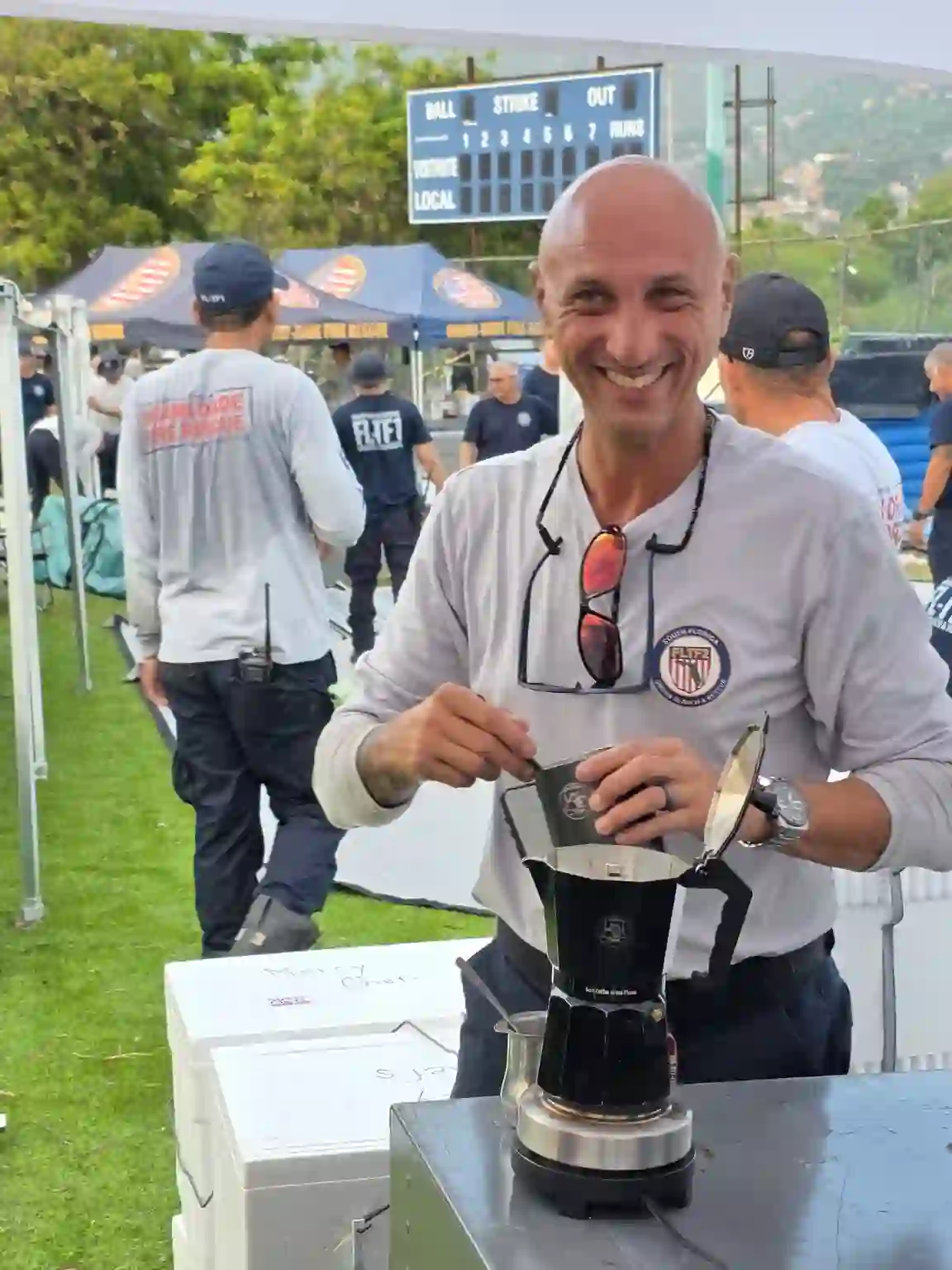 Search Grounds founder Miguel Ferrer smiling as he brews cafecito in a branded moka pot at a task force event